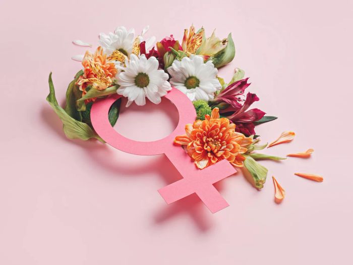 A symbol of femininity adorned with vibrant spring flowers and greenery, set against a soft pastel pink backdrop