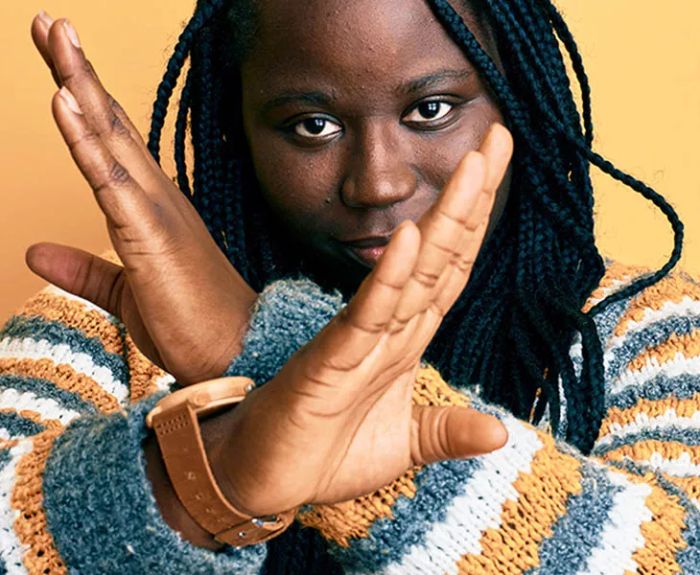 Young Black Woman with Braids Wearing a Winter Sweater in a Rejection Pose