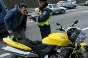 A police officer performing a roadside breathalyzer test on a driver.