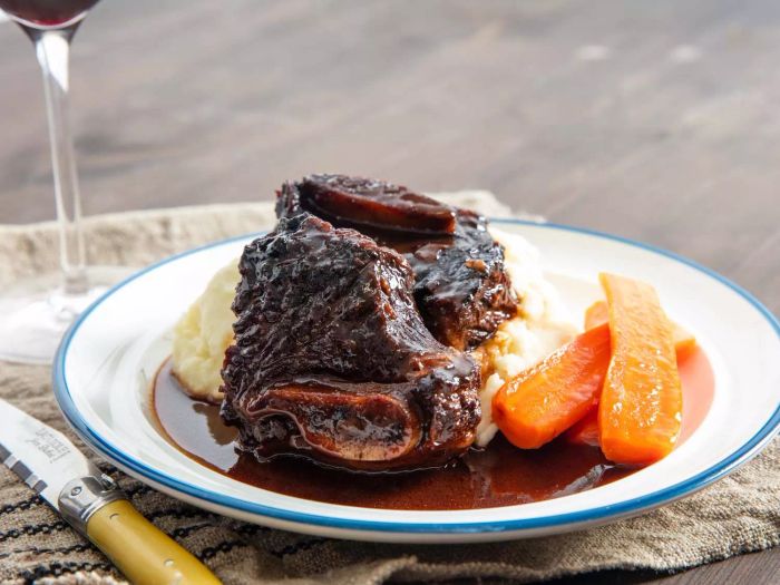 Red-wine braised beef short ribs served on a plate with rich, reduced sauce, mashed potatoes, and carrots on the side