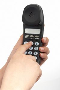 A hand dialing numbers on a telephone or mobile device.