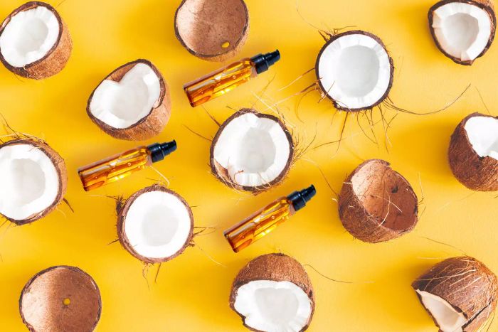 A bird's-eye view of dry coconuts sliced in half, arranged in a pattern on a vibrant yellow backdrop.