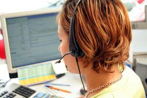 A call center agent using a headset while working on a desktop computer.