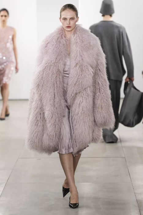 A model takes the runway at Michael Kors wearing an oversized pink jacket.