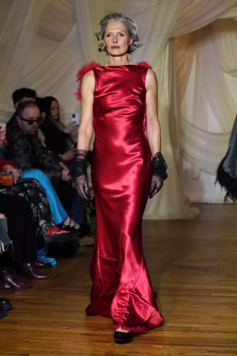 A model graces the Christian Cowan runway in a high-neck, silk red gown.