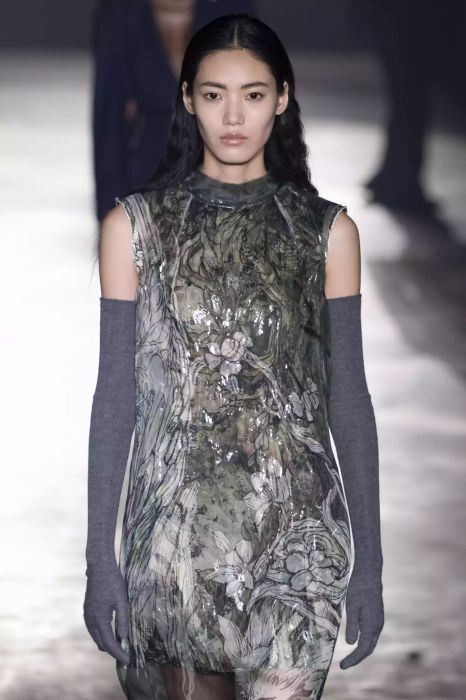 A model walks the runway at Jason Wu's show, showcasing natural, radiant skin paired with a gray patterned mini dress.