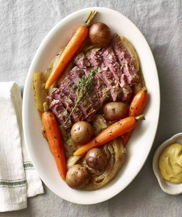 Corned beef and cabbage served on a large plate with carrots and potatoes.