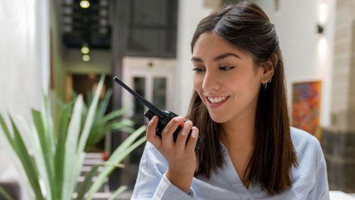 A woman speaking into a walkie-talkie.