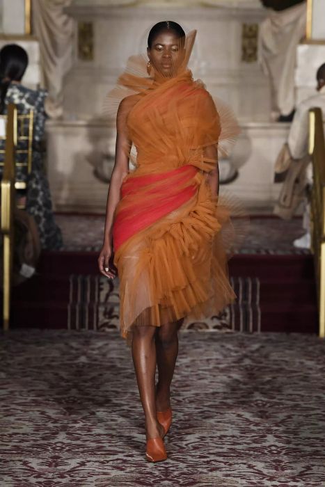 A model struts the runway at the Christian Siriano show in an orange tulle dress.