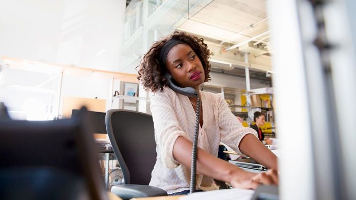 A woman using a landline phone in her office setting