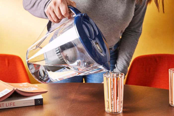 A person is seen pouring water from the Epic Water Filter Pitcher into a glass.