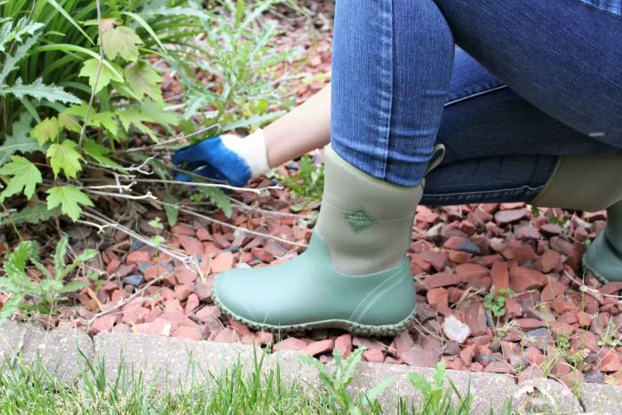 Person kneeling outdoors, wearing The Original Muck Boot Company Women's Muckster II Mid Boot