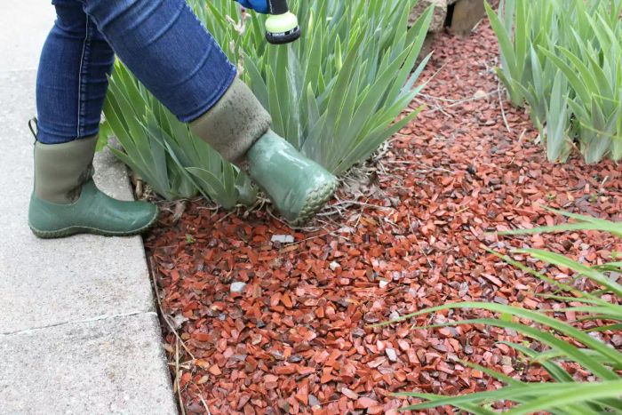 Person standing on a stone floor in The Original Muck Boot Company Women's Muckster II Mid Boot, watering plants.
