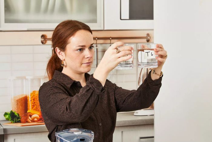 A person holding glasses of water filtered through the Brita Rapids Stream Water Pitcher