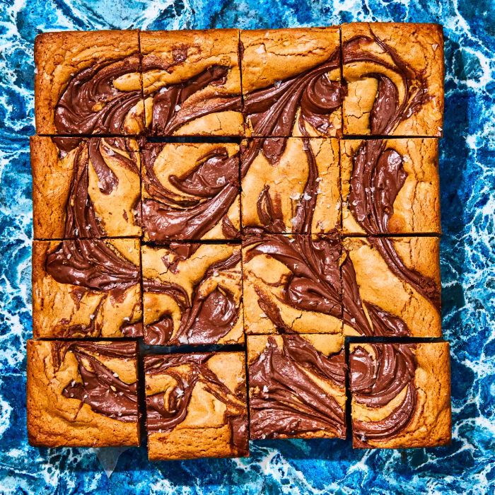 Hazelnut Swirl Blondies cut into squares on a blue surface