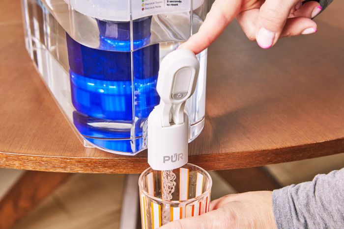 A person presses down on the Pur Plus 30-Cup Dispenser