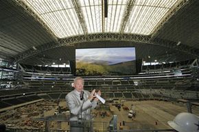 Jerry Jones standing in front of the Dallas Cowboys' colossal scoreboard.