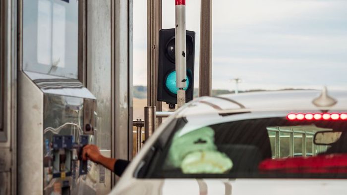 A motorist paying the toll fee at a toll booth.