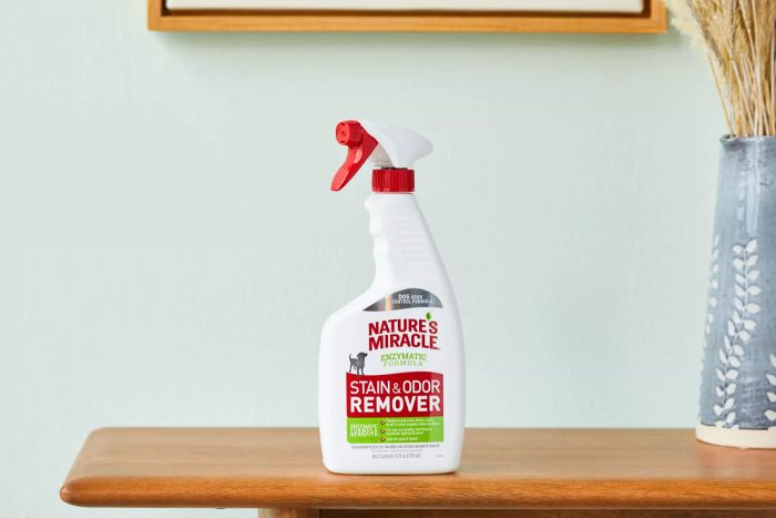 A bottle of Nature's Miracle Cat Enzymatic Stain and Odor Remover displayed atop a wooden table.