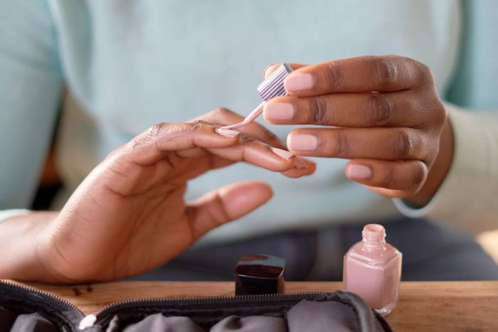 Applying pink nail polish to natural nails