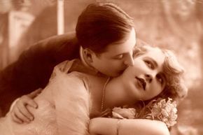 A sepia-toned photo of a couple dressed in early 20th-century fashion.