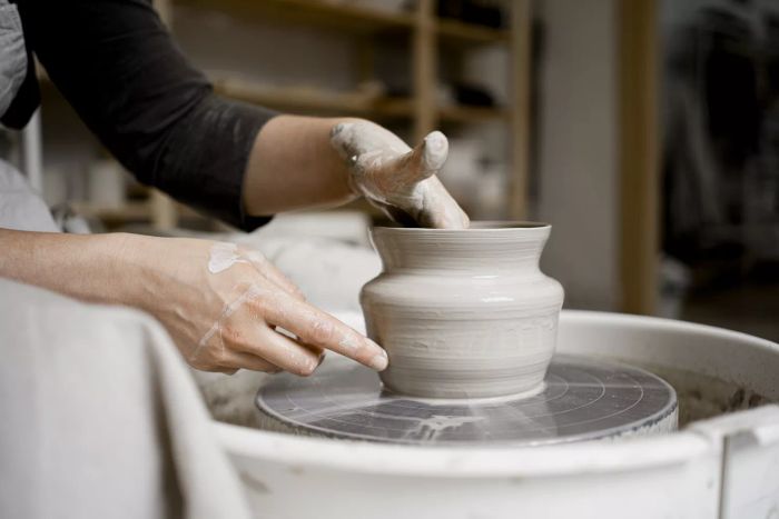 A young craftswoman shaping a flower pot on a pottery wheel