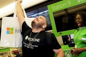 The first person to purchase an Xbox One at the midnight release event at the Florida Mall in Orlando, Florida, holds their new console high in celebration.