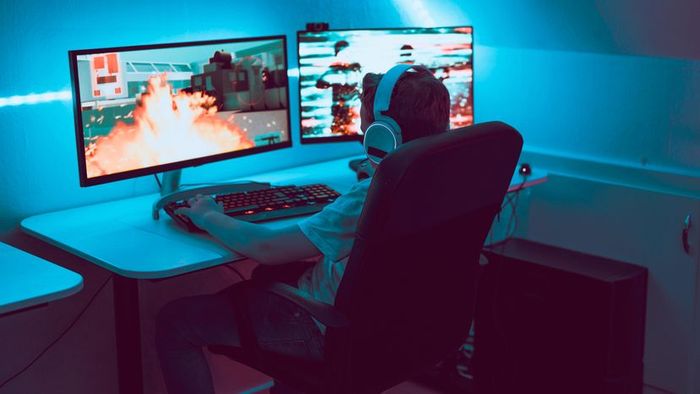 A young player immersed in a shooter game on his computer.