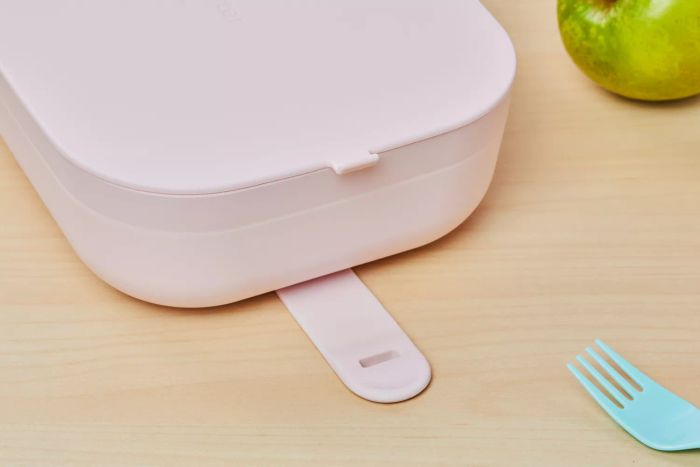 Close-up shot of the W&P Porter Lunch Box on a table with a green apple and a fork
