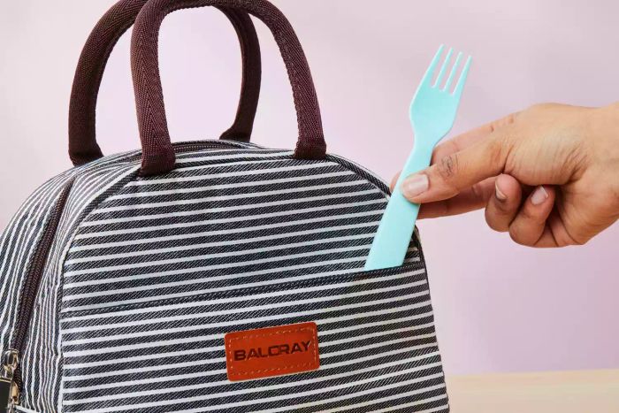 A person placing a fork into the pocket of the Baloray Insulated Lunch Bag