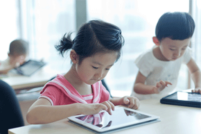 A young boy and girl using tablet PCs.