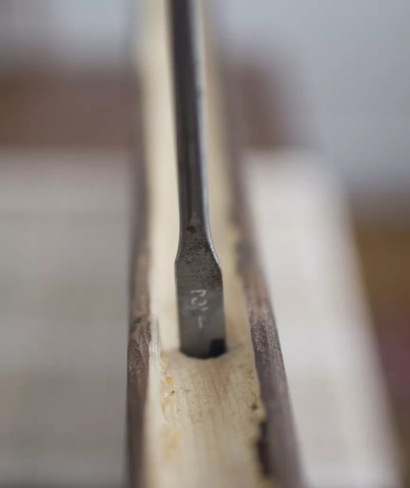 Drill bit making its way into the pine shelf wood