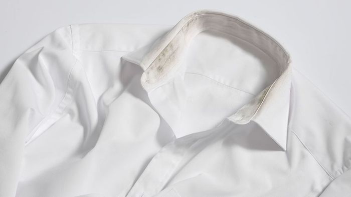 A white dress shirt showing yellow and black stains around the inner collar.