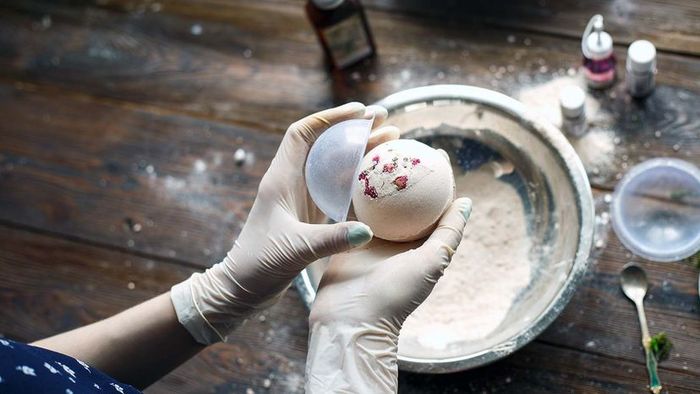 A person wearing gloves, preparing bath bombs using household ingredients.