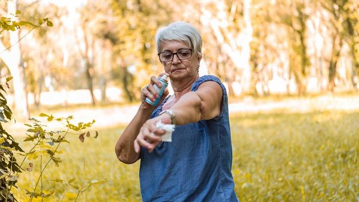 A woman applying bug spray to protect herself from insects