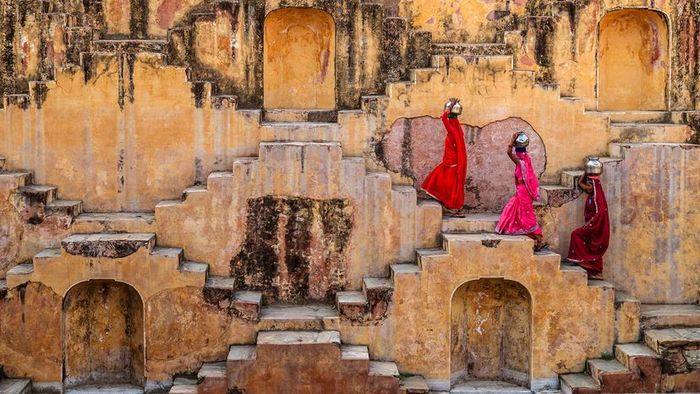 Women in India are seen carrying water from a stepwell.