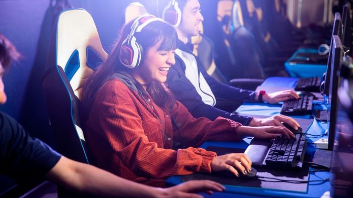 A group of teenagers gathered around their PCs, enjoying a video game session.