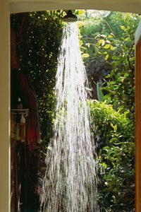 Water cascading from a waterfall showerhead in an outdoor shower setting. 