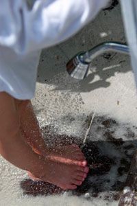 A person using an outdoor shower to rinse sand off their feet.&nbsp;