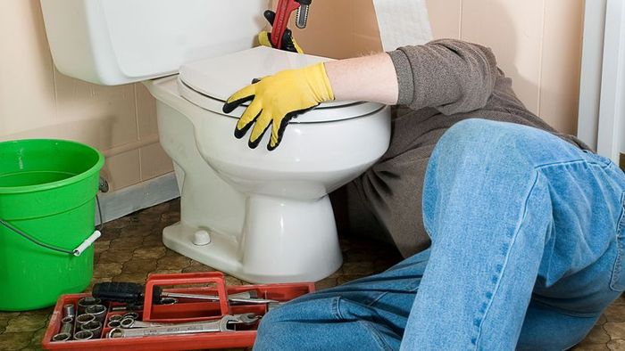 person fixing a toilet