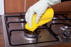 a gloved hand scrubbing a gas stove