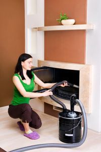 woman vacuuming ashes from fireplace