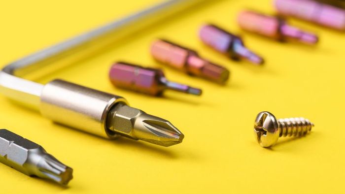 A screwdriver featuring various bit sizes set on a yellow background.