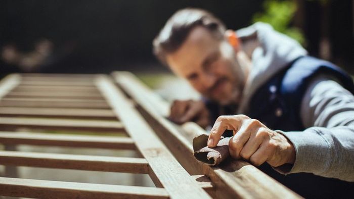 A person sanding down an old handrail.