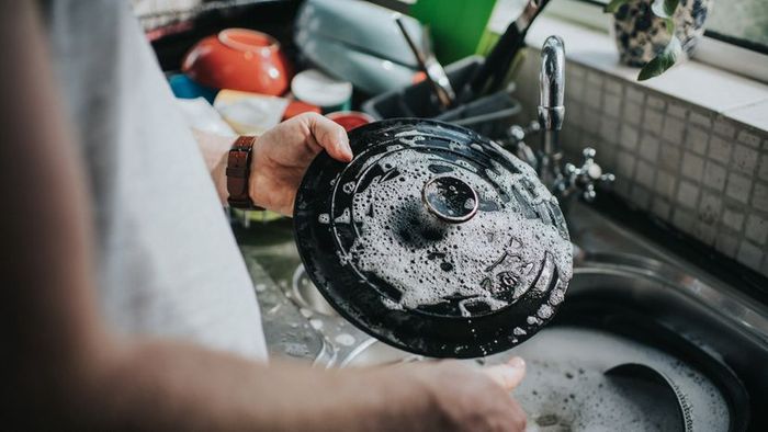 A person washing dishes in the sink.