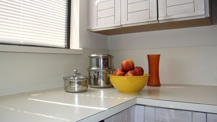 A kitchen countertop adorned with a bowl of apples, pots, and a vase.