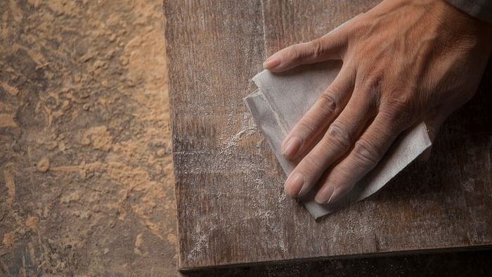 A person applying sandpaper to a wooden surface.
