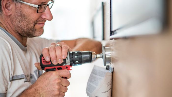A close-up shot of a handyman using a drill to create a hole.