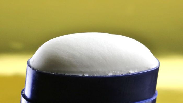 A white deodorant stick set against a bright yellow backdrop