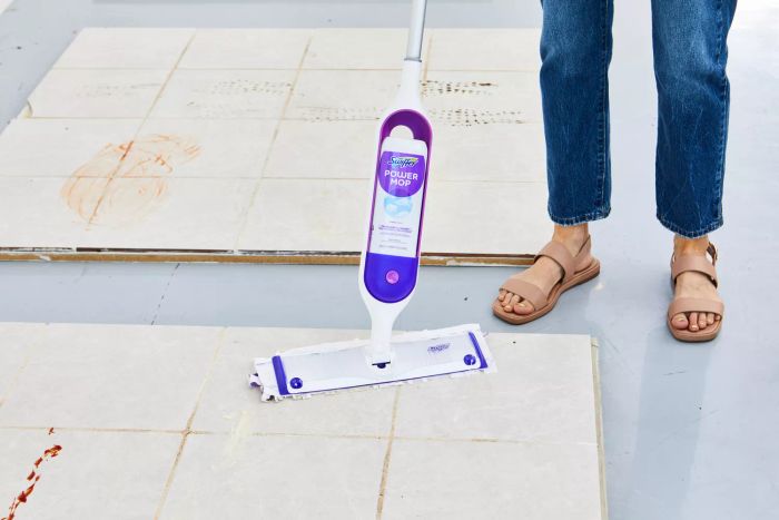 A person testing the Swiffer mop on a tile floor.